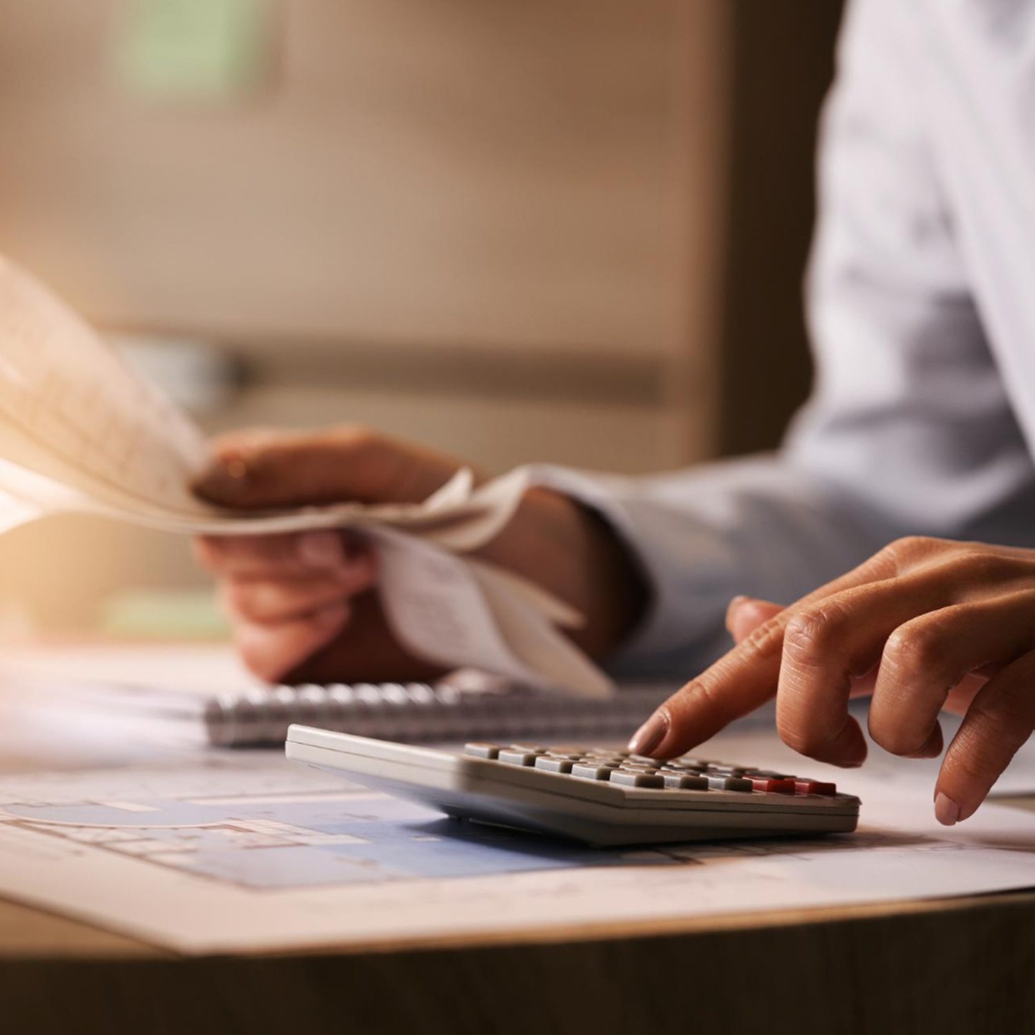 closeup-economist-using-calculator-while-going-through-bills-taxes-office-scaled