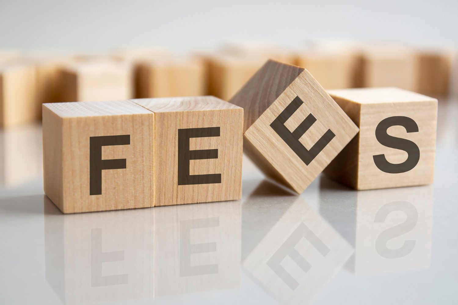 word-fees-wooden-cubes-gray-background-reflection-mirrored-surface-table-selective-focus